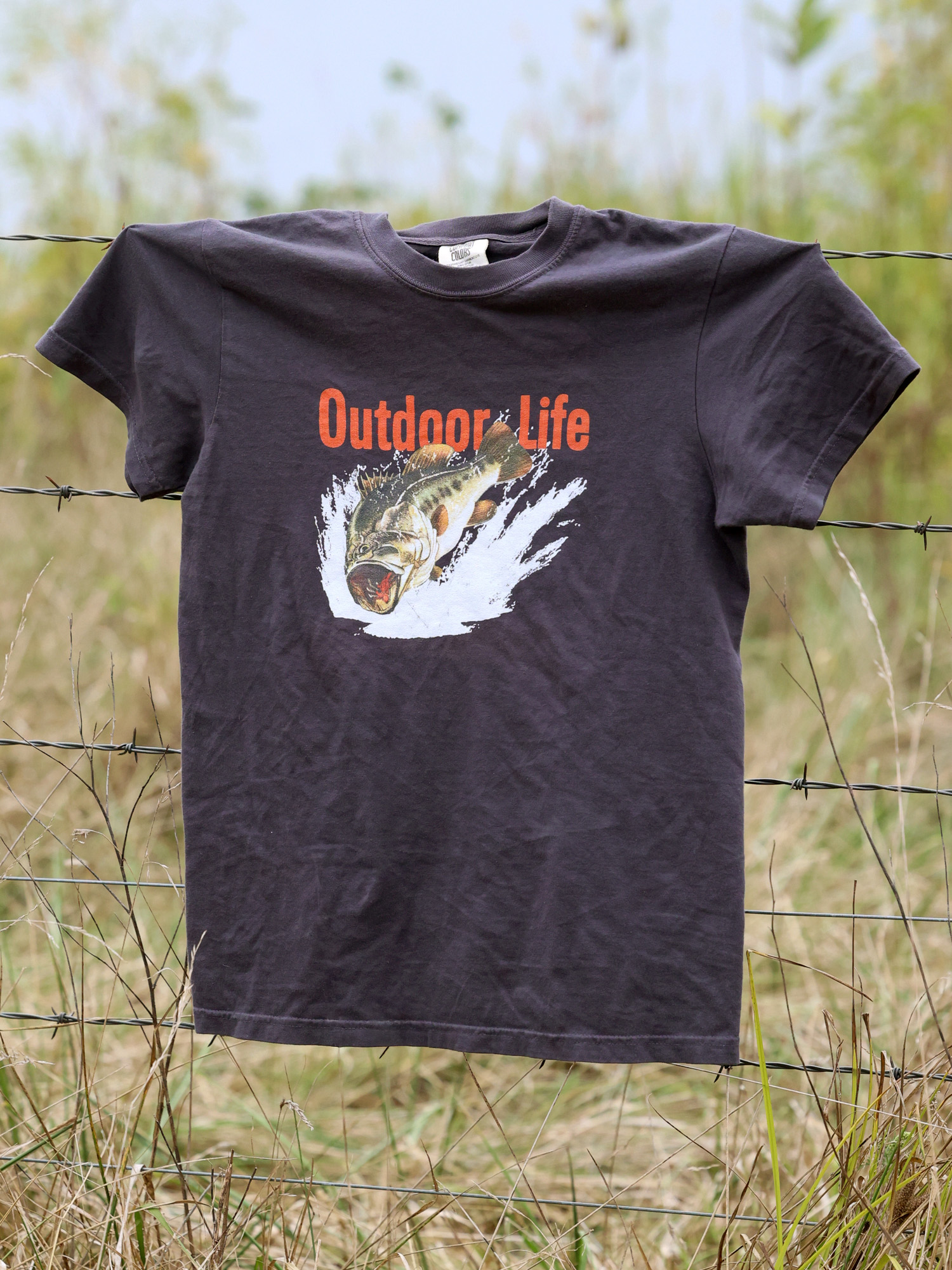 A dark gray outdoor life t-shirt with a big bass on it