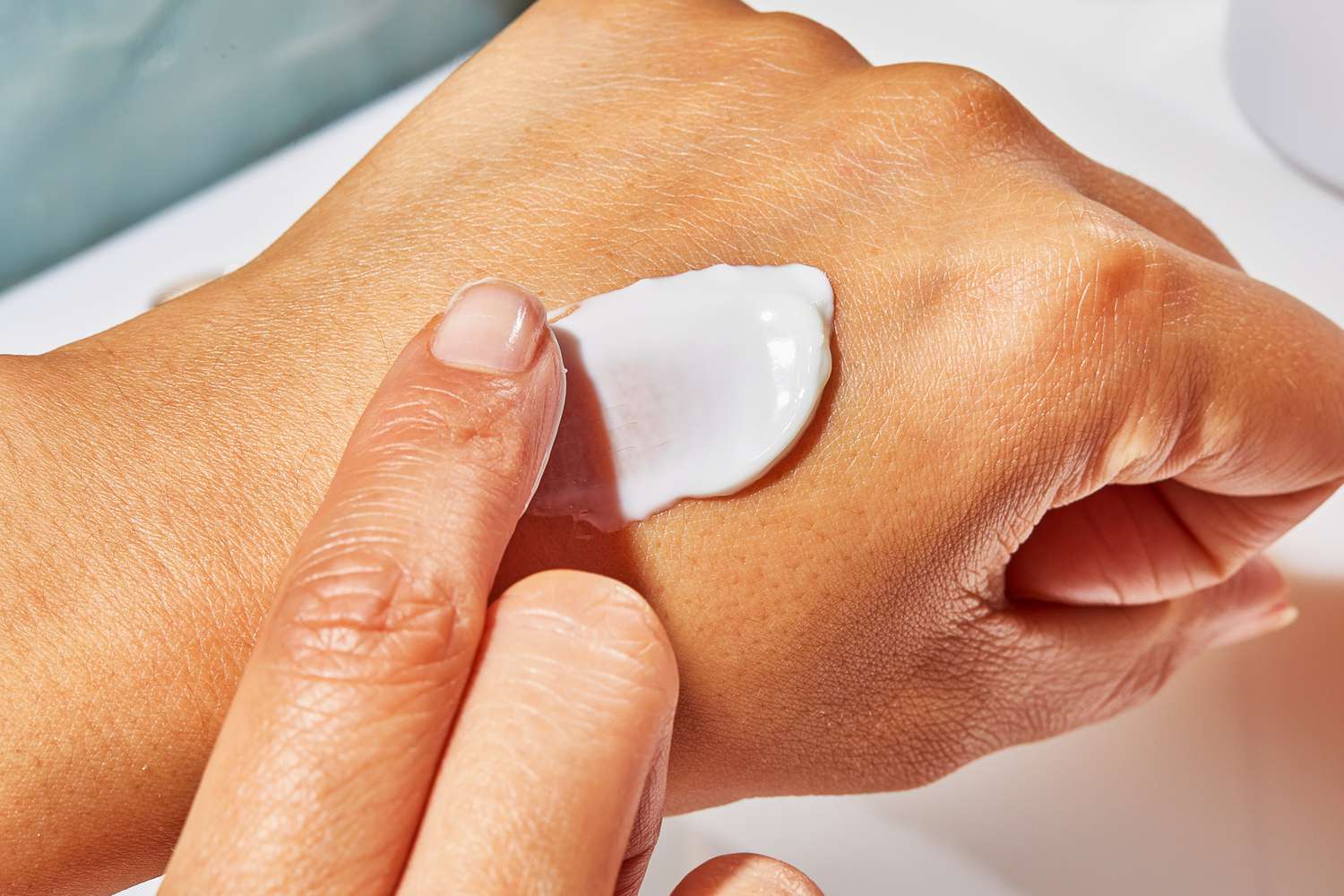 A person applies Dr. Barbara Sturm Face Cream Rich to their hand